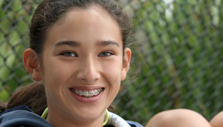 smiling girl with braces at a baseball field