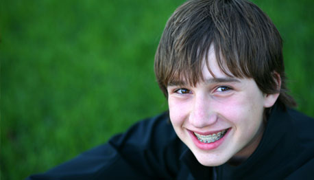 smiling boy on grass with braces